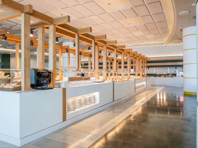 Moderne Hotelbuffetstationen mit Holzrahmen und weißen Theken in einem hellen Raum.