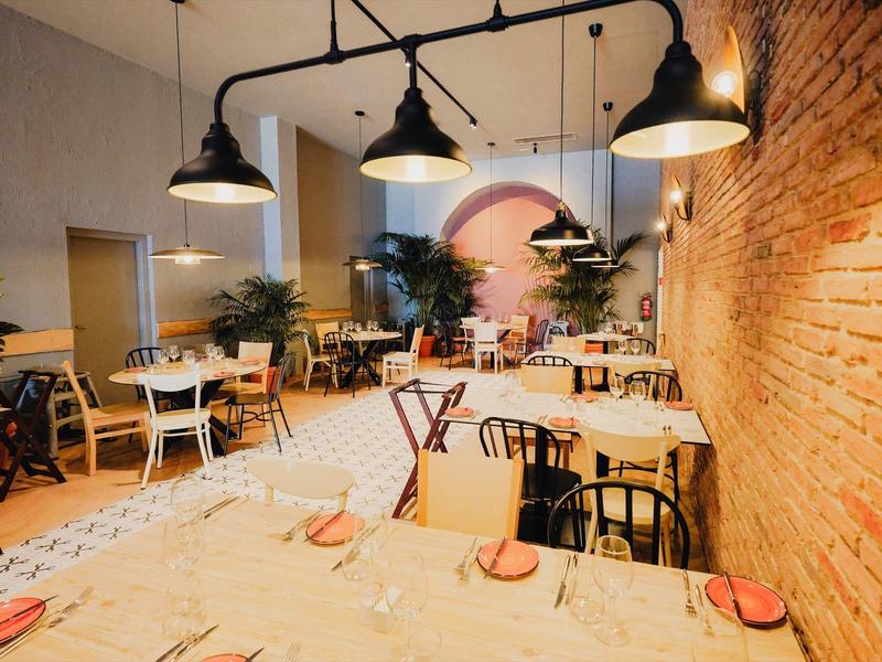 Gemütlicher Innenbereich eines Cafés mit Holzmöbeln, Pflanzen und hängenden Lampen.