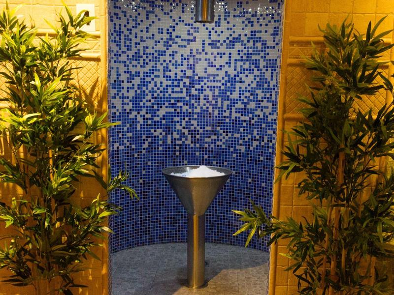 Fuente de agua moderna con azulejos azules y plantas en un entorno de bienestar.