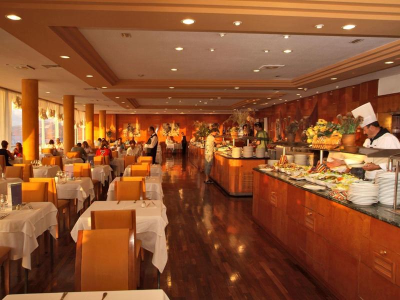 Gran buffet con diferentes platos y clientes en un restaurante iluminado.