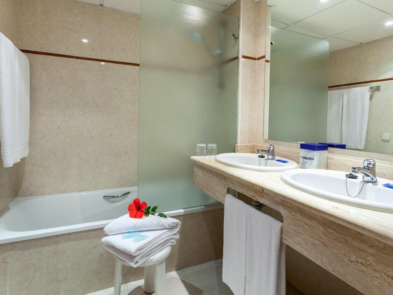 Baño moderno con bañera, dos lavabos y toallas en una habitación de hotel.