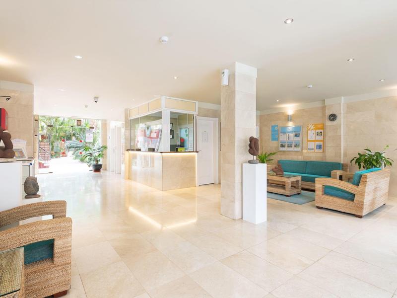 Hall d'hôtel lumineux avec réception moderne et coin salon aux accents bleus.