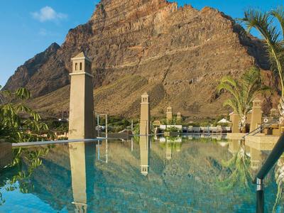 Pool mit Reflexion von zwei Türmen vor einem großen Felsen und blauem Himmel