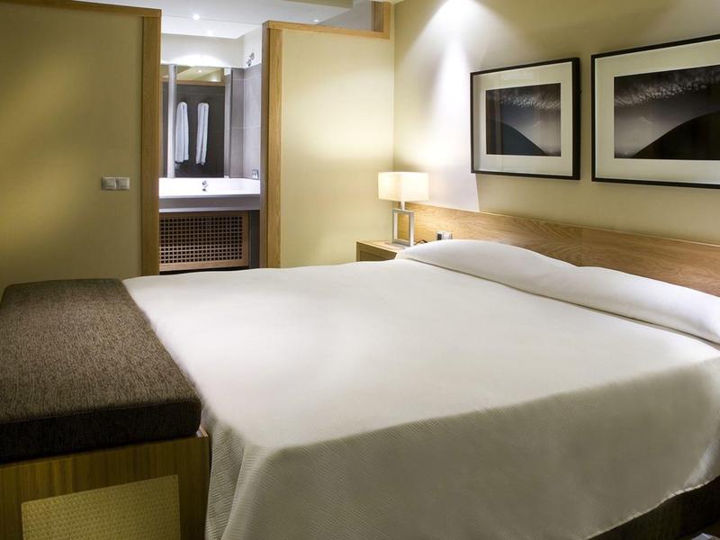 Chambre d'hôtel moderne avec grand lit et vue sur la salle de bains.