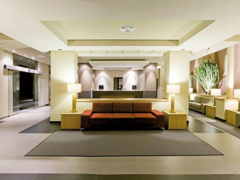 Hall d'hôtel moderne avec canapés élégants, éclairage chaleureux et plantes décoratives.