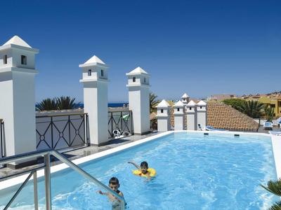 Buitenzwembad met kinderen en witte pilaren onder blauwe lucht