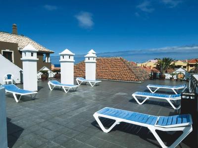 Dakterras met ligstoelen en uitzicht op de blauwe zee en lucht.