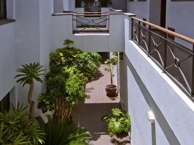 Binnenplaats van een hotel met witte muren, planten en zonnige lucht.