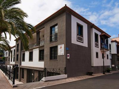 Zweistöckiges Gebäude mit braun-weißen Wänden und roten Ziegeldächern an einer Straßenecke.