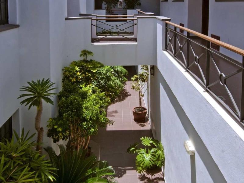 Binnenplaats van een hotel met witte muren, planten en zonnige lucht.