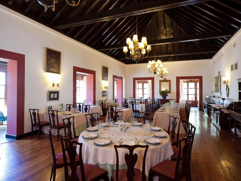 Sala da pranzo elegante con tavoli rotondi e sedie in legno sotto un soffitto scuro.