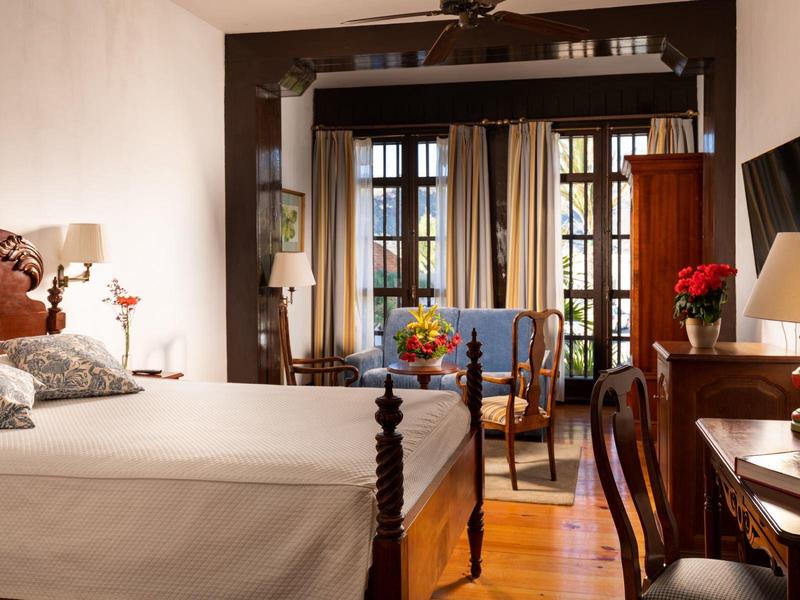 Camera d'hotel elegante con letto, scrivania, sedia e ampia finestra luminosa.