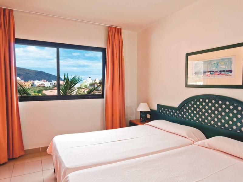 Lichte hotelkamer met twee bedden en uitzicht op bergen door het raam.