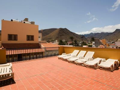 Ampia terrazza con lettini e vista sulle montagne in una giornata soleggiata.