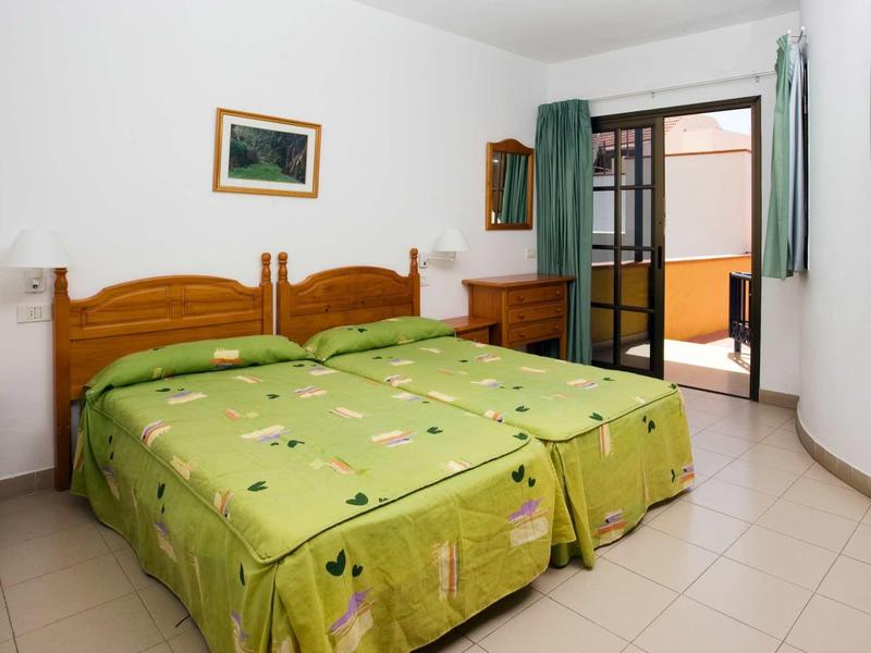 Bright hotel room with two single beds and access to a balcony or terrace.