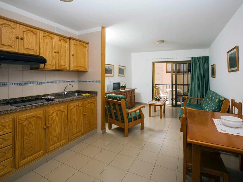 Brightly furnished apartment with kitchen, dining area, and seating area with sofa.