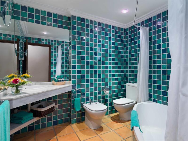 Nowoczesna łazienka z niebieskimi kafelkami, wanną, toaletą, bidetem i umywalką w hotelu.