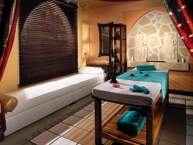 Przytulny pokój do masażu z dwoma stołami i przyciemnionym światłem.