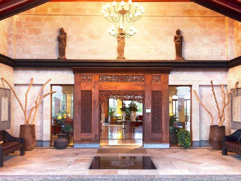 Eleganckie wejście do hotelu z drewnianą dekoracją, żyrandolem i miejscami do siedzenia