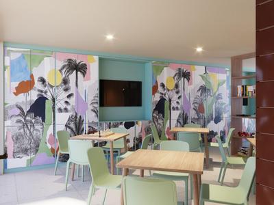 Modern dining area with colorful wall mural and light green chairs in a hotel.