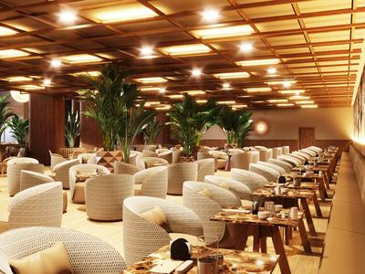 Spacious hotel lounge area with white wicker chairs and wooden tables under warm ceiling lights.