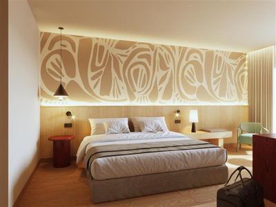 Modern hotel room with large bed, wood paneling, and decorative wall lighting.