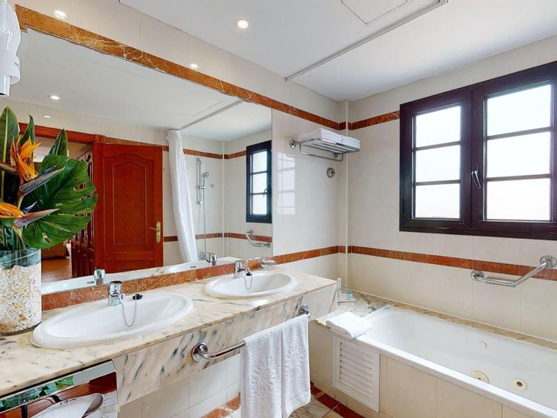 Bagno luminoso con grande vasca da bagno, specchio e piante decorative.