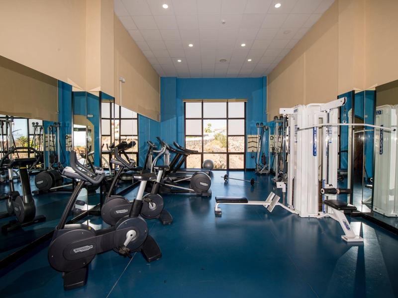 Palestra moderna con cyclette, macchine per il fitness e grandi finestre in un hotel.