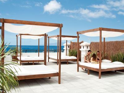 Drei Holzbetten mit weißen Matratzen und blauen Himmel am Meer im Hintergrund.