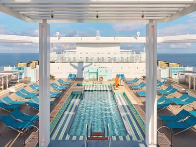 Hotelpool auf einem Kreuzfahrtschiff mit blauen Liegestühlen und Blick auf das Meer.