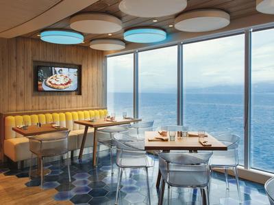Modernes Hotelrestaurant mit großen Fenstern und Blick auf das Meer bei Tag.