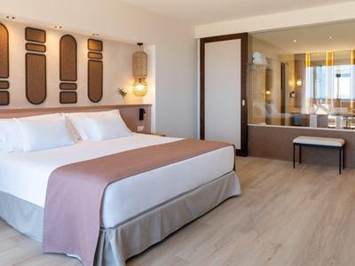 Modernes Hotelzimmer mit großem Bett, Holzfußboden und Blick auf ein Badezimmer mit Badewanne.