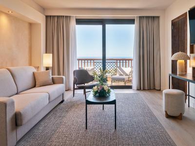 Modern eingerichtetes Wohnzimmer mit Balkon und Meerblick in einem Hotel.