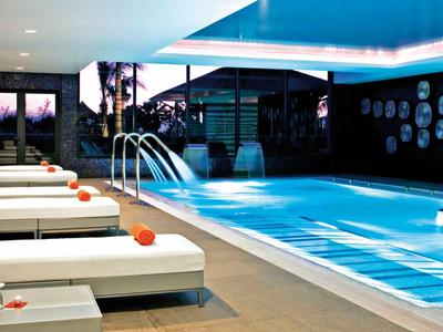 Elegant indoor pool with loungers and decorative wall tiles in a modern hotel.