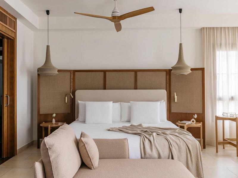 Elegant slaapkamer met groot bed, twee hanglampen, plafondventilator en zithoek.