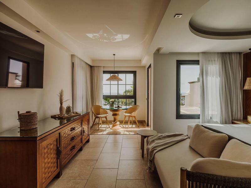 Elegante eetruimte met houten meubels en bank in een open, lichte kamer met grote ramen.