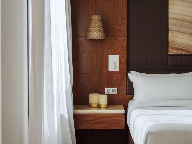 Slaapkamer met wit bed, houten wand, nachtkastje en gordijn.