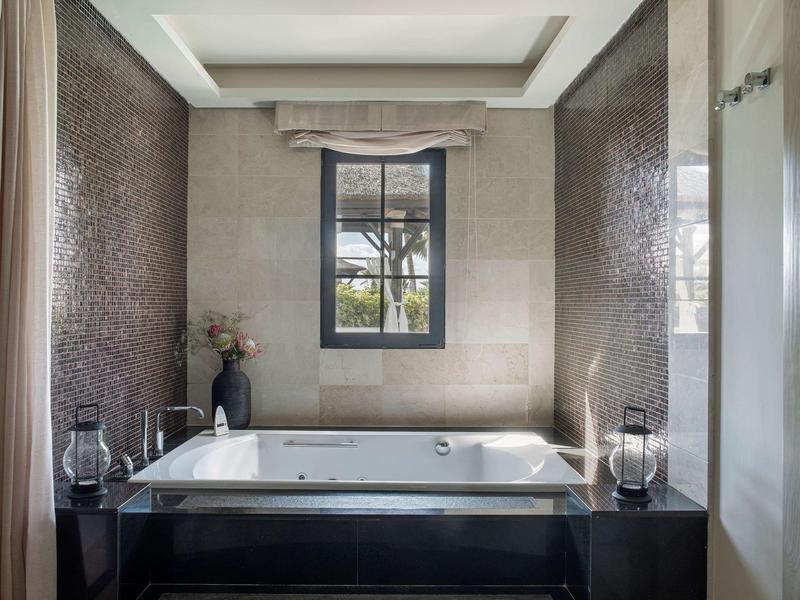 Luxe badkuip in moderne badkamer met raam en subtiele decoratie.