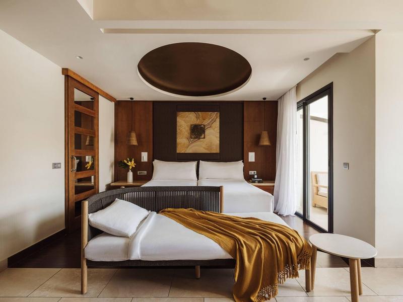 Moderne slaapkamer met twee bedden, bruine accenten en toegang tot een balkon.