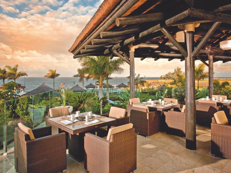 Dakterras met comfortabele zitplaatsen en uitzicht op bergen bij zonsondergang.