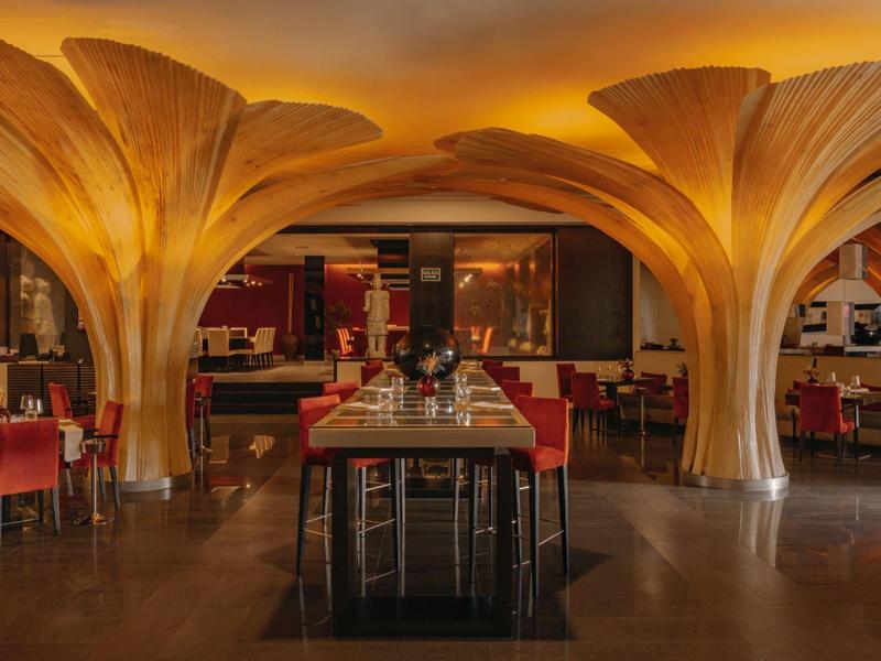 Modern restaurant met decoratieve gouden zuilen en stijlvolle zitgedeeltes.