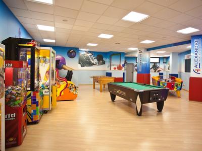 Sala giochi ben illuminata con tavolo da biliardo e varie macchine arcade.