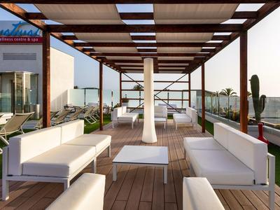 Dachterrasse mit Holzpergola, weißen Sitzmöbeln und Glasgeländer bei Tageslicht.