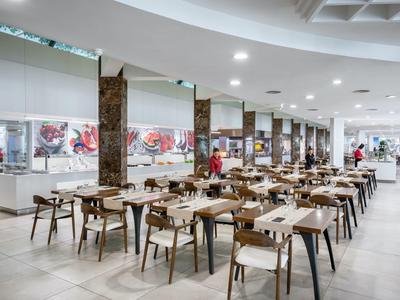 Große, moderne Kantine mit Holzstühlen und Tischen, hellen Böden und weißer Decke.