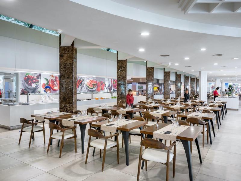 Große, moderne Kantine mit Holzstühlen und Tischen, hellen Böden und weißer Decke.