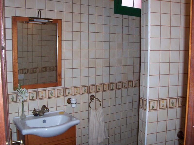 Kleines Badezimmer mit weiß-karierten Wandfliesen, rechteckigem Spiegel und weißem Waschbecken.