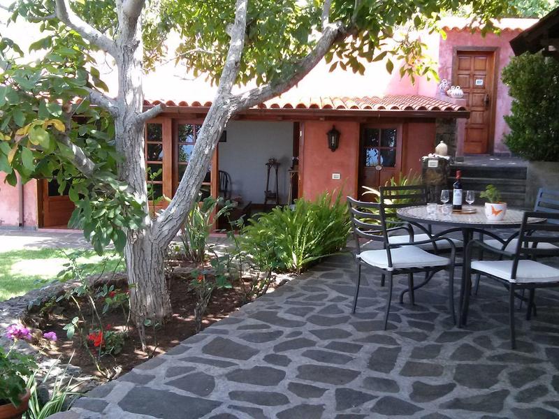 Dvůr s dlážděnou podlahou, stromem a posezením vedle tradičního domu.