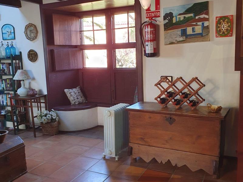 Příjemný pokoj s dřevěnými trámy, kachlovými kamny a okenním sedátkem s polštáři.