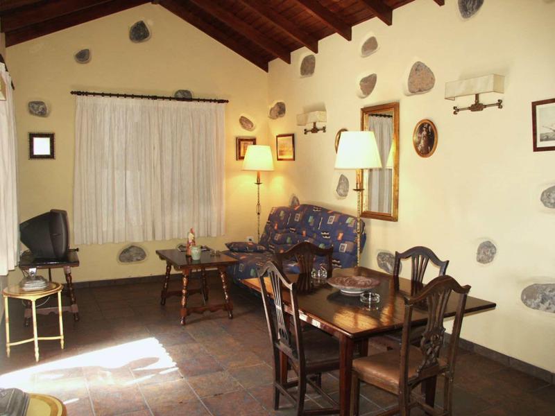 Gezellige hotelkamer met houten meubels, stoelen, bank en verlichting aan stenen muur.