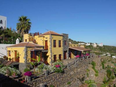 Żółty dom z ogrodem i kamiennym murem pod czystym niebieskim niebem na wsi